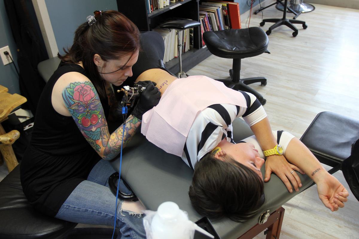 Carrie Black of Bigfoot Tattoo Tattooing a Client 