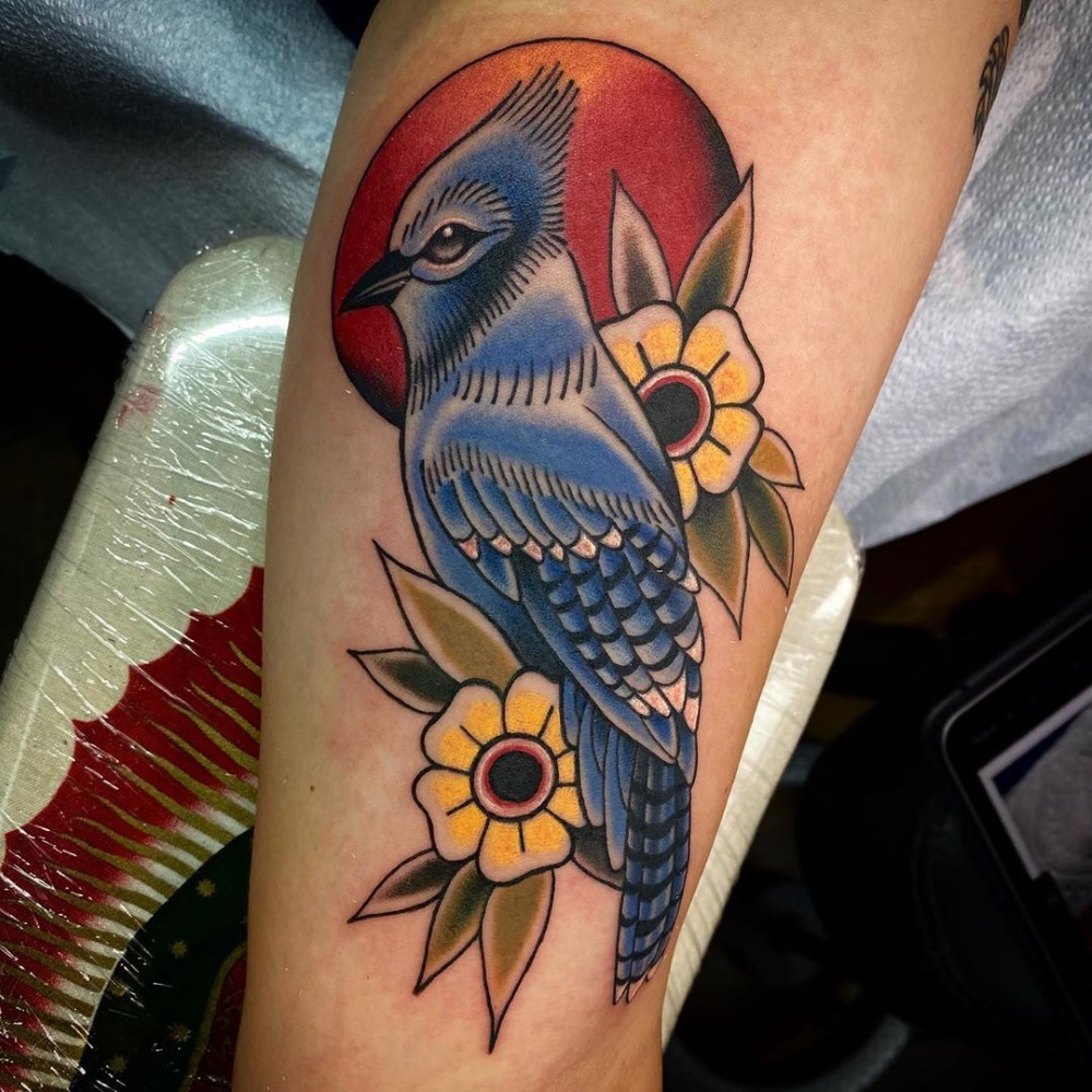 Bluejay tattoo with floral backdrop and red sun by tattoo artist Mandy Fabrizi