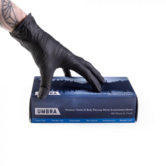 Tattoo artist wearing Umbra nitrile tattoo glove presenting a box of Umbra gloves Tattoo artist wearing Umbra nitrile tattoo glove presenting a box of Umbra gloves