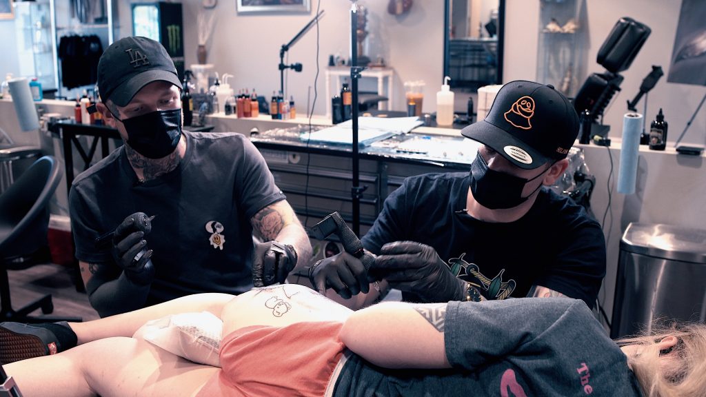 Harlan Kantner and Kasey Gonzalez tattooing a thigh together