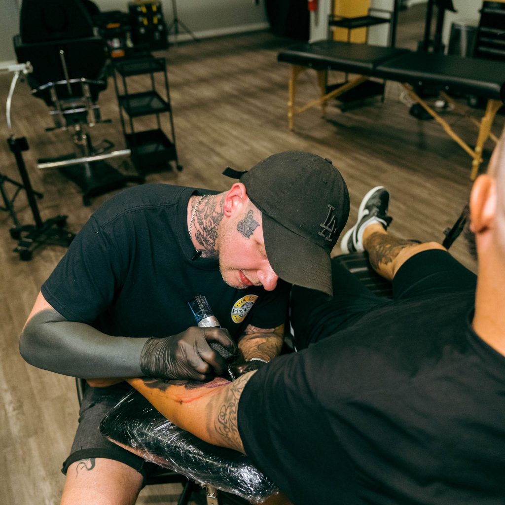 Successful ProTeam artist Kasey Gonzalez tattooing black and grey realism on a client's arm