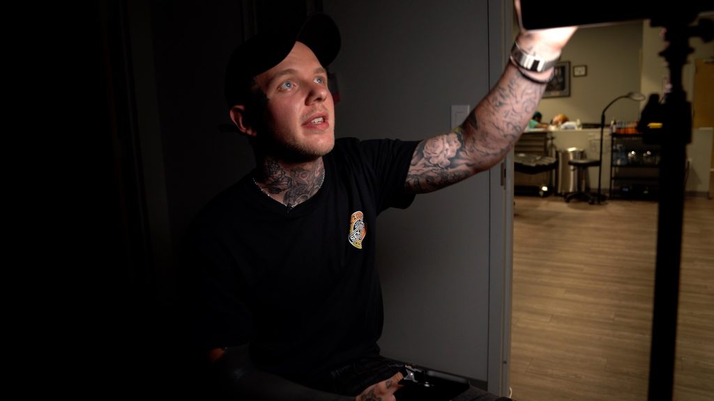 Tattoo artist Kasey Gonzalez adjusts the lighting in his studio, preparing to take a photo of a tattoo.