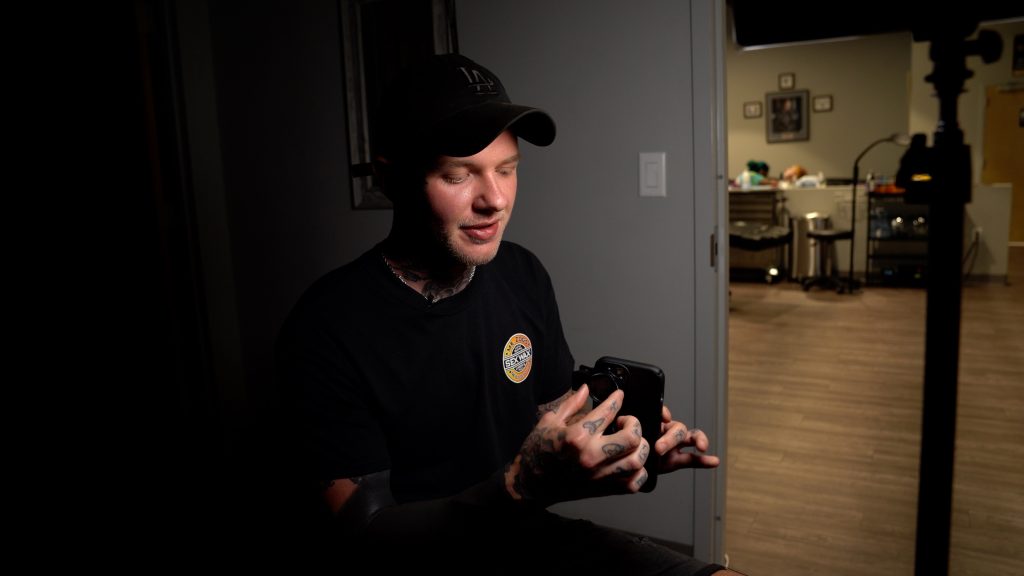 Tattoo artist Kasey Gonzalez holds his iPhone and CPL (circular polarized lens).