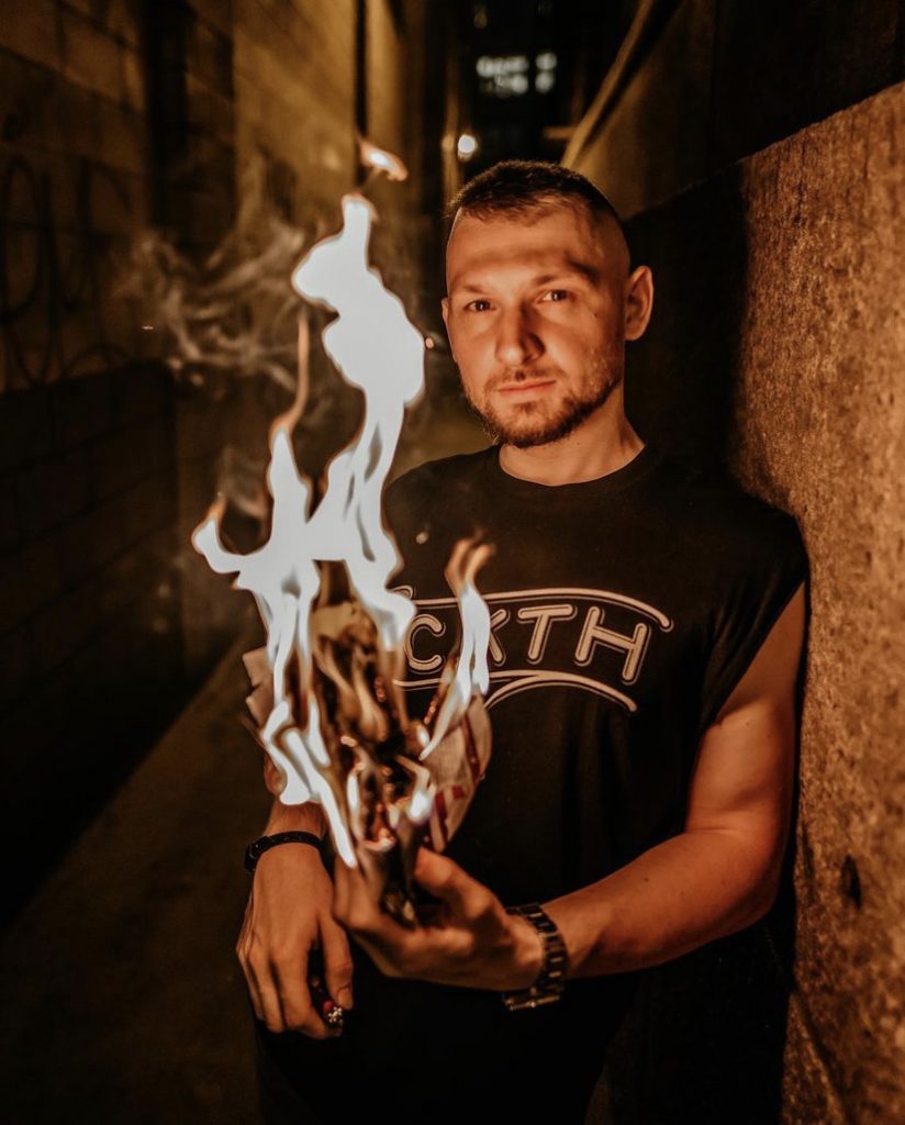 Tattoo artist Levgen Kenesh holding a flaming piece of paper