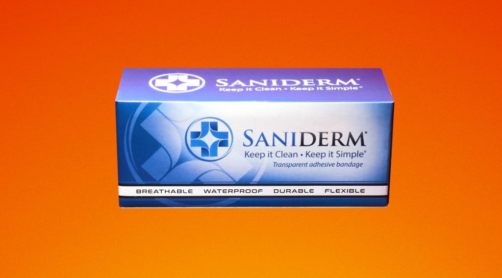 Box of Saniderm tattoo aftercare bandages over top an orange background