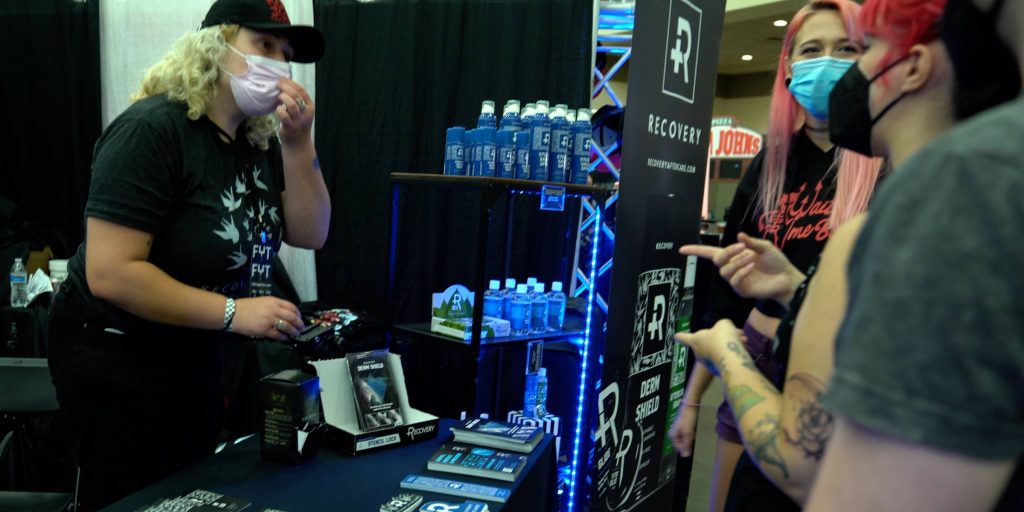 Booth worker selling Recovery aftercare at a tattoo convention