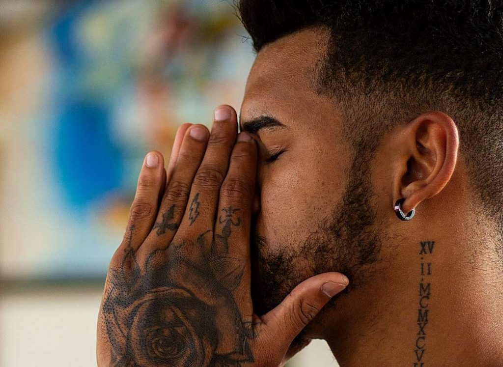 Tattooed man with hands over his mouth looking burnt out