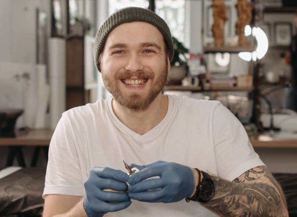 Happy looking tattoo artist with gloved hands 
