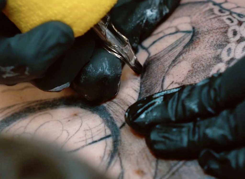 Close up of tattoo artist Casey Hart performing a black and gray tattoo