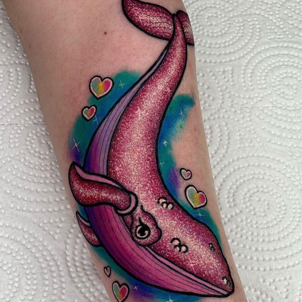 Tattoo client with sparkly pink whale tattoo on forearm
