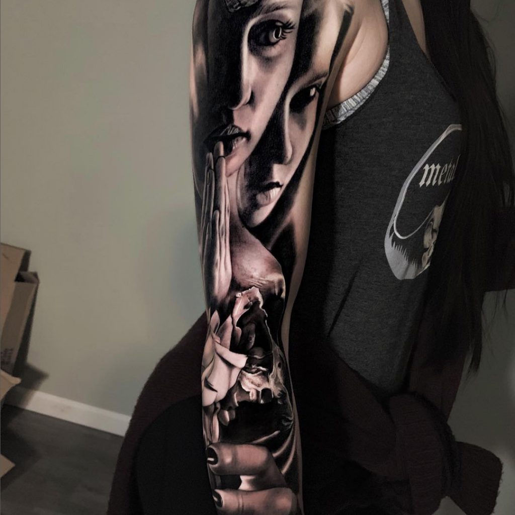 Tattoo client with hyperrealistic black and gray portrait tattoo on outer arm
