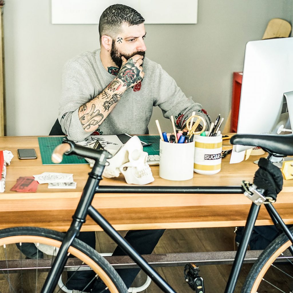 Tattoo artist practicing good mental health by booking appointments on his computer