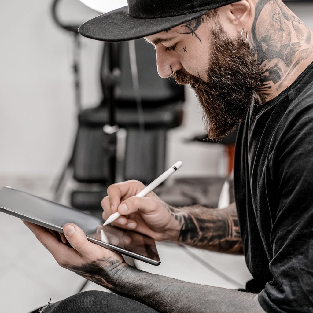 Tattoo artist drawing on his iPad and doing creative work for his mental health