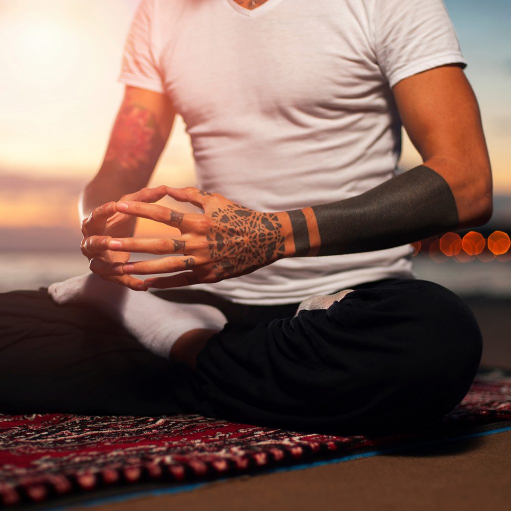 Tattoo artist meditating on a yoga mat outside