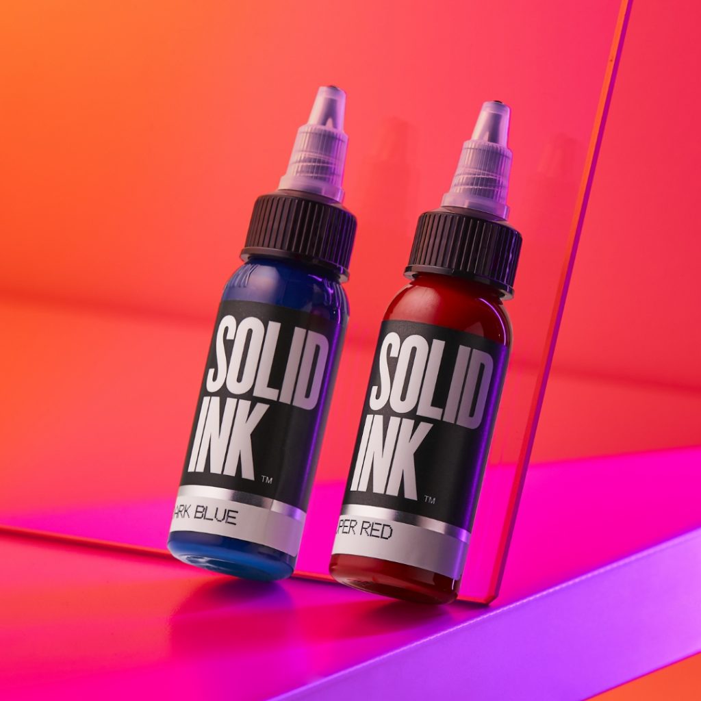 Two Solid Ink bottles leaned back against a sheet of plastic