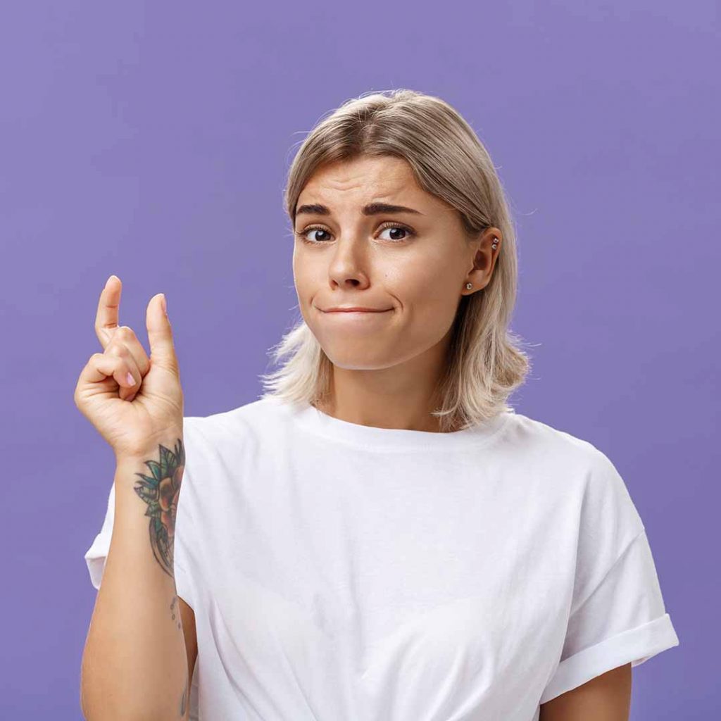 Girl with tattoo pinching her fingers together to indicate something small
