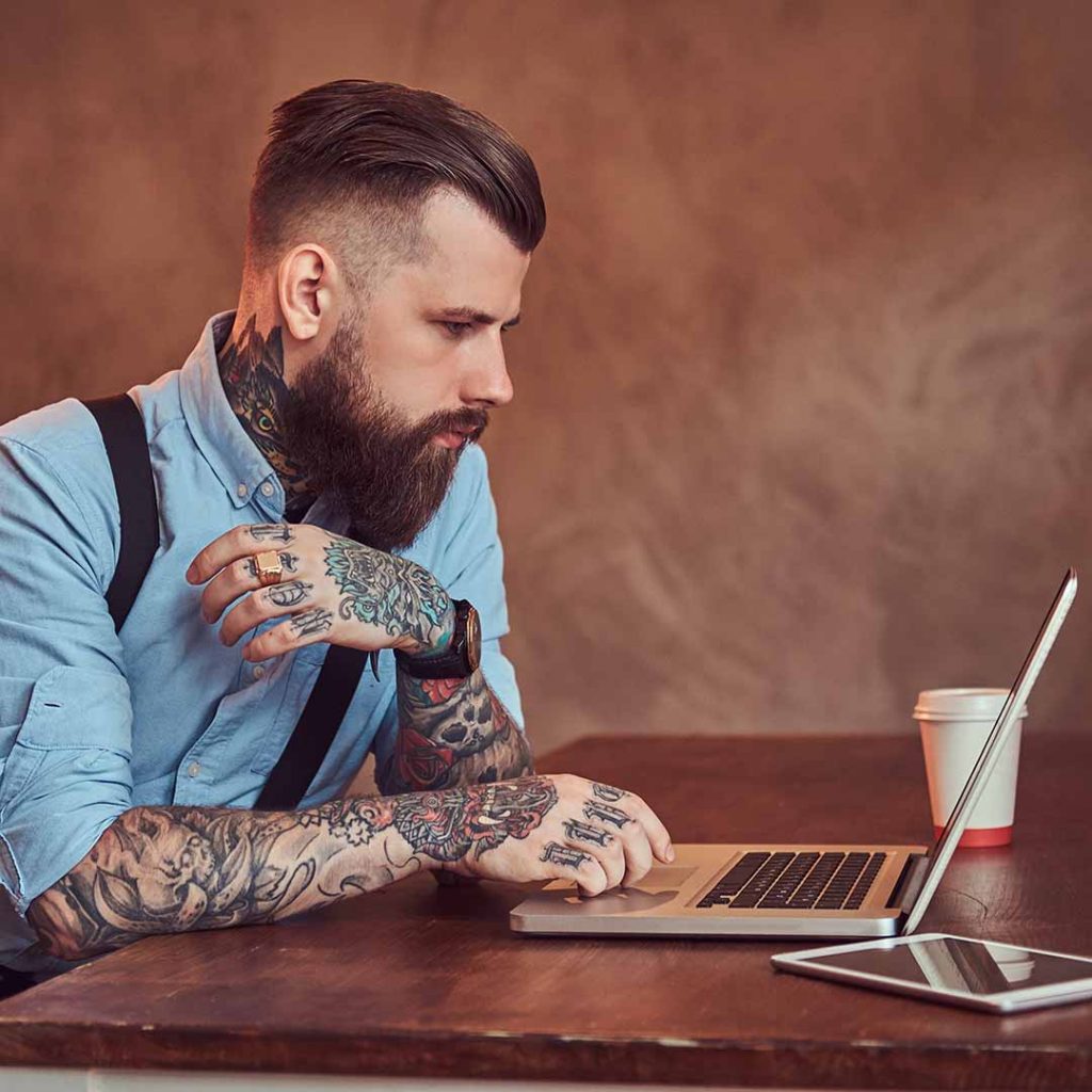 Tattoo artist at a laptop doing his taxes
